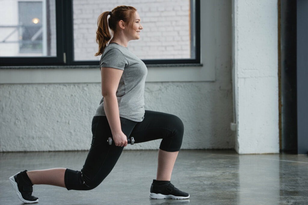 Mulher com roupa de academia fazendo exercício com peso